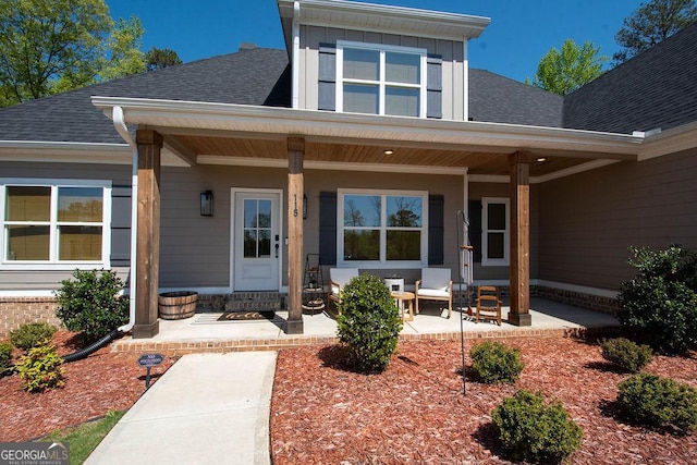 entrance to property featuring board and batten siding, covered porch, and roof with shingles