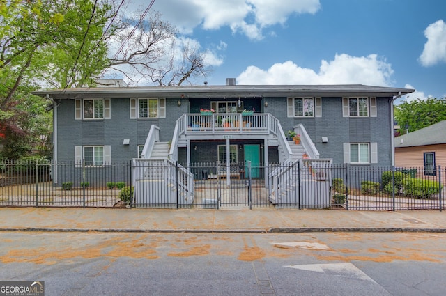 view of front of house with stairway, brick siding, and a fenced backyard