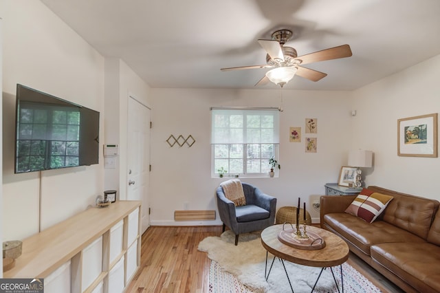 living room featuring a ceiling fan, baseboards, and light wood-style floors