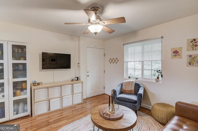living room featuring ceiling fan, baseboards, and light wood finished floors