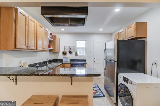 kitchen featuring washer / dryer, a peninsula, a sink, dark stone countertops, and stainless steel appliances