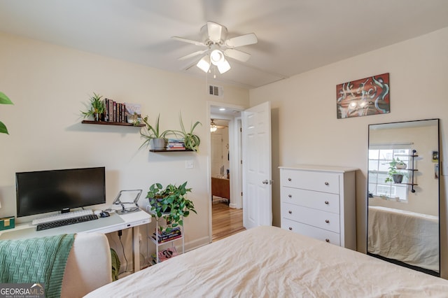 bedroom featuring a ceiling fan, visible vents, and wood finished floors