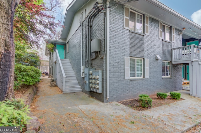 view of side of home featuring brick siding and stairway