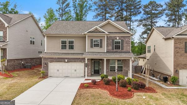 craftsman-style house with an attached garage, concrete driveway, covered porch, and brick siding