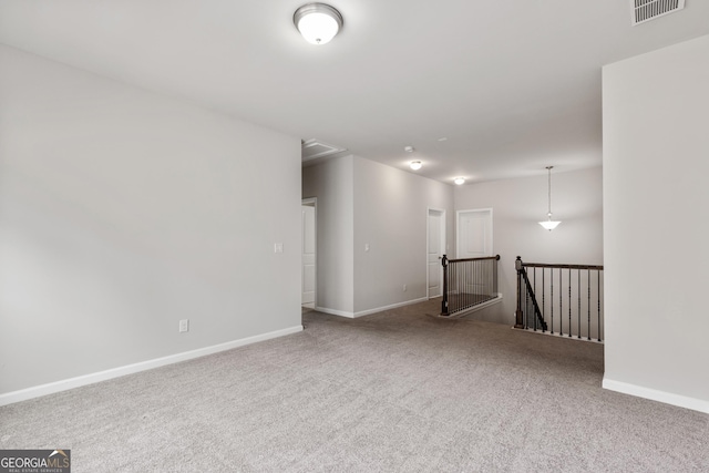 carpeted spare room with attic access, baseboards, and visible vents