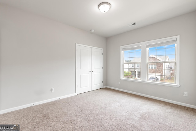 unfurnished bedroom featuring visible vents, baseboards, a closet, and carpet
