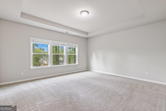carpeted empty room featuring visible vents, baseboards, and a raised ceiling