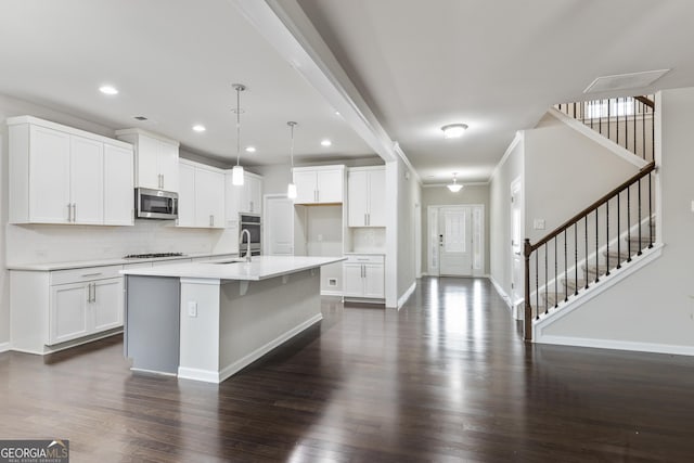 kitchen featuring stainless steel microwave, baseboards, backsplash, crown molding, and gas stovetop