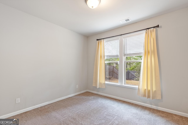 unfurnished room featuring carpet flooring, visible vents, and baseboards