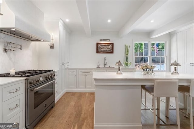 1305 Old Woodbine Rd, Atlanta, GA 30319 - kitchen featuring custom range hood, high end range, light wood-type flooring, beam ceiling, and a sink