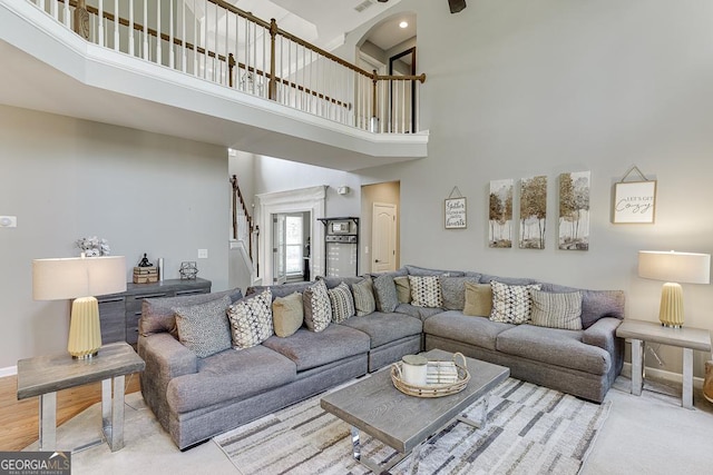 living area featuring baseboards, a high ceiling, and stairs