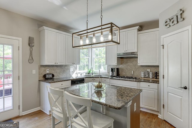 kitchen featuring under cabinet range hood, light wood finished floors, a sink, and gas stovetop