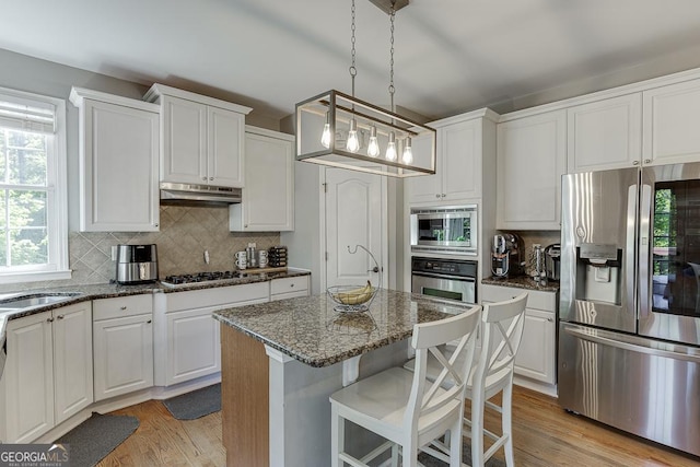 kitchen featuring stainless steel appliances, under cabinet range hood, light wood-type flooring, and white cabinetry