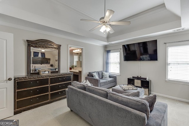 living room with ceiling fan, light colored carpet, ornamental molding, and a raised ceiling