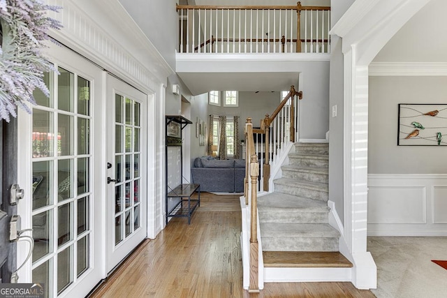 staircase featuring french doors, a high ceiling, and ornamental molding