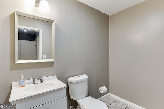 bathroom with toilet, marble finish floor, vanity, and baseboards