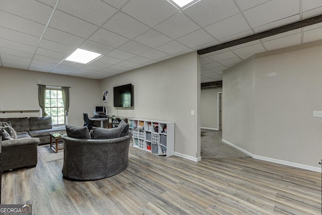 living room with a drop ceiling, baseboards, and wood finished floors