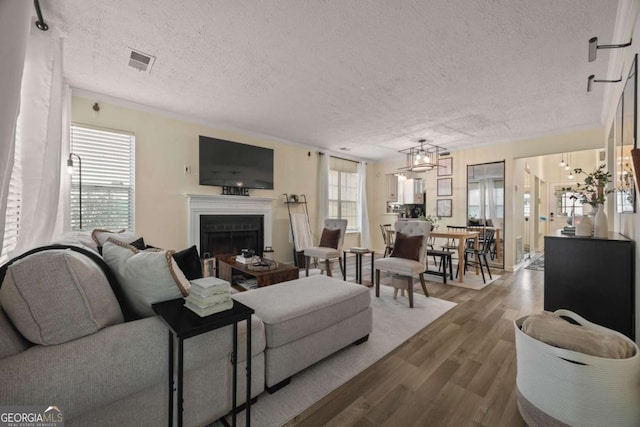 living area with a textured ceiling, wood finished floors, a fireplace, and visible vents