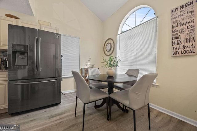 dining area with light wood finished floors, baseboards, and lofted ceiling