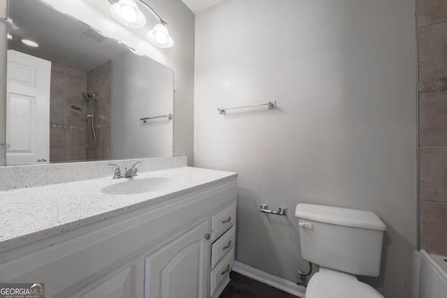 full bathroom with a tile shower, toilet, vanity, and wood finished floors