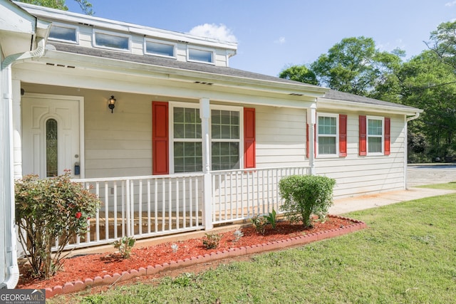 view of front of house with a shingled roof, a front lawn, and covered porch