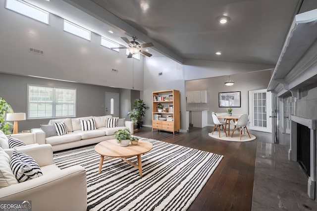 living room with dark wood-style floors, visible vents, a ceiling fan, baseboards, and high vaulted ceiling