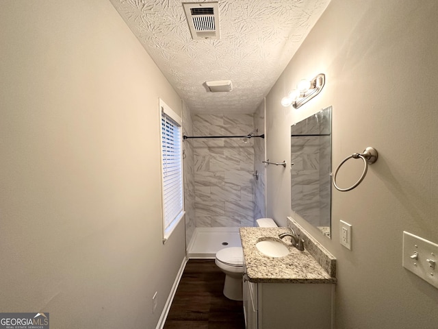 659 Country Club Rd, Newnan, GA 30263 - bathroom with a textured ceiling, tiled shower, vanity, visible vents, and wood finished floors