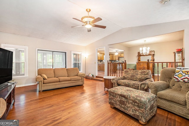 living room featuring baseboards, wood finished floors, ceiling fan with notable chandelier, and vaulted ceiling