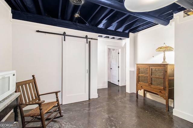 sitting room featuring concrete floors, a barn door, and baseboards