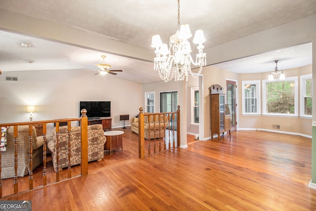 living area featuring visible vents, lofted ceiling with beams, baseboards, wood-type flooring, and ceiling fan with notable chandelier
