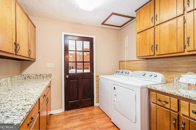washroom with washer and dryer, cabinet space, light wood-style flooring, and a textured ceiling