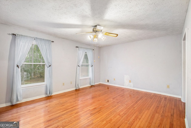empty room with a textured ceiling, ceiling fan, baseboards, and light wood-type flooring