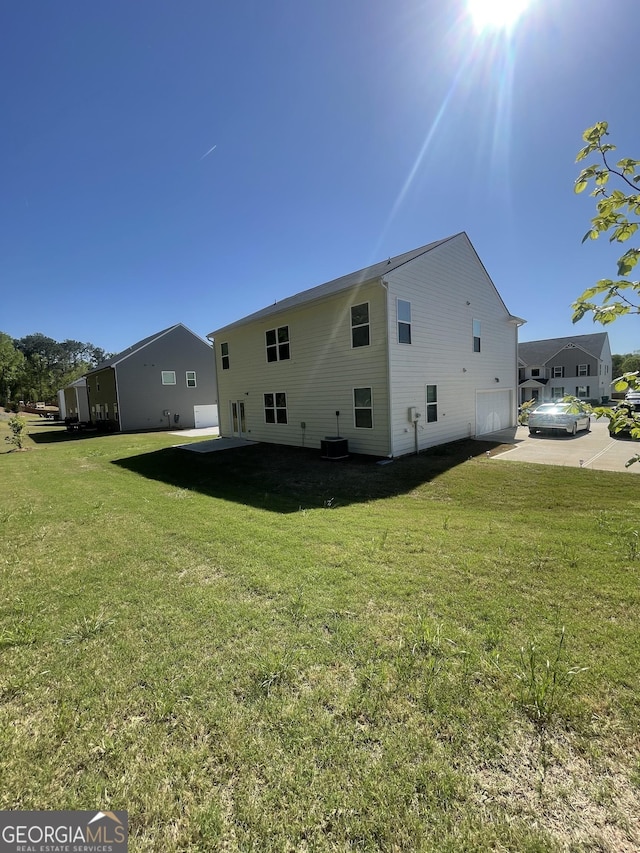 205 Sullivan St, Hampton, GA 30228 - rear view of house with a lawn, concrete driveway, central AC, and an attached garage