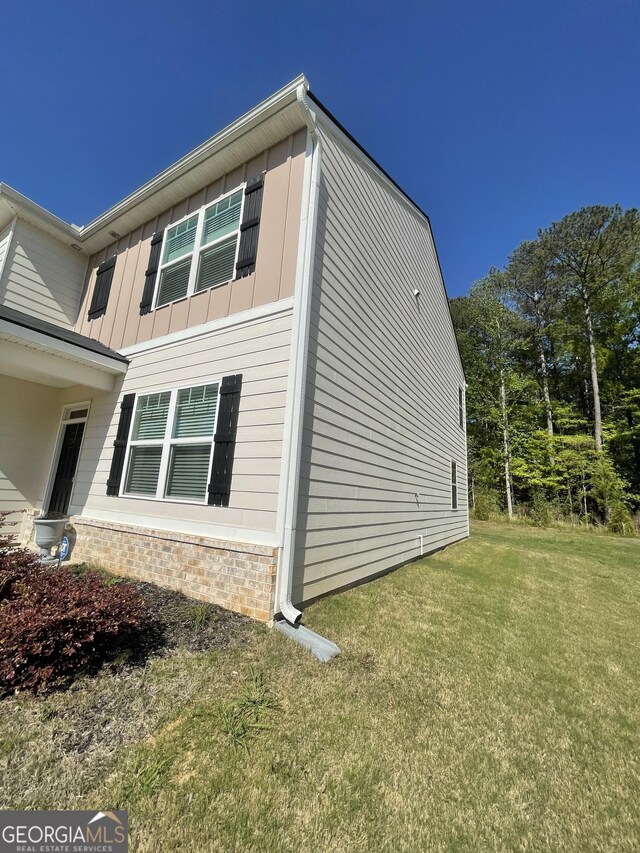 205 Sullivan St, Hampton, GA 30228 - view of side of property with board and batten siding, a yard, and stone siding