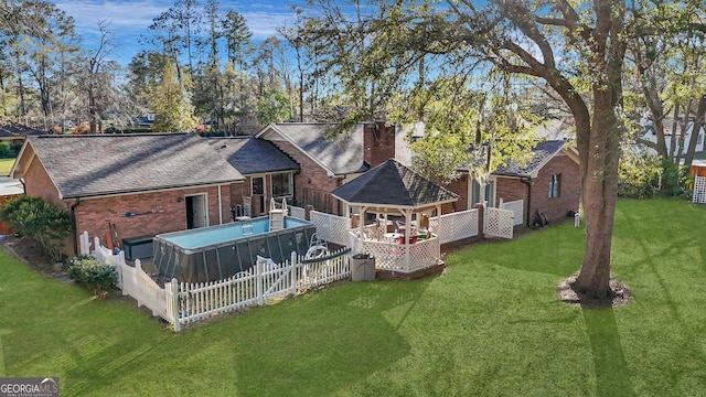 rear view of property with a shingled roof, a chimney, a lawn, and brick siding