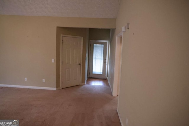 spare room with baseboards, light carpet, and a textured ceiling