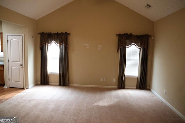spare room with visible vents, light colored carpet, baseboards, and lofted ceiling