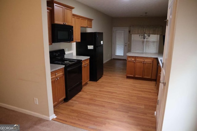 kitchen with baseboards, light wood-type flooring, light countertops, and black appliances