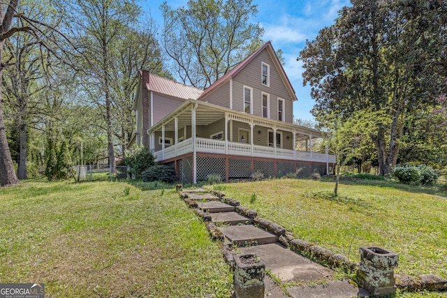 rear view of house featuring a yard and metal roof