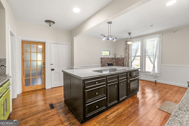 kitchen with pendant lighting, visible vents, black appliances, hardwood / wood-style floors, and wainscoting
