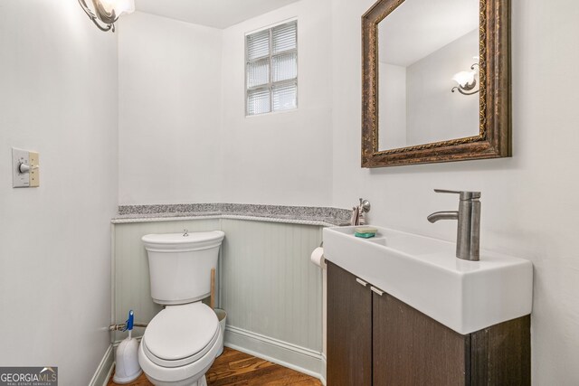 bathroom featuring toilet, vanity, wood finished floors, and baseboards