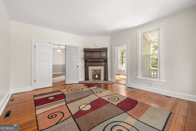 unfurnished living room with visible vents, baseboards, hardwood / wood-style flooring, a fireplace, and crown molding