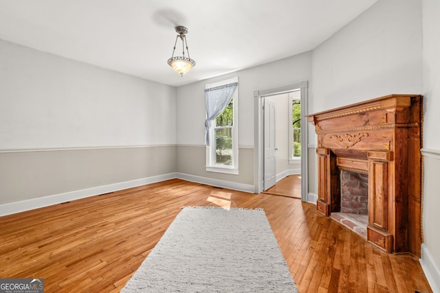 unfurnished living room with wood-type flooring, baseboards, and a fireplace