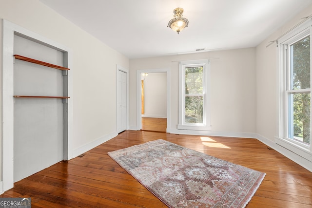 bedroom with wood-type flooring, visible vents, multiple windows, and baseboards