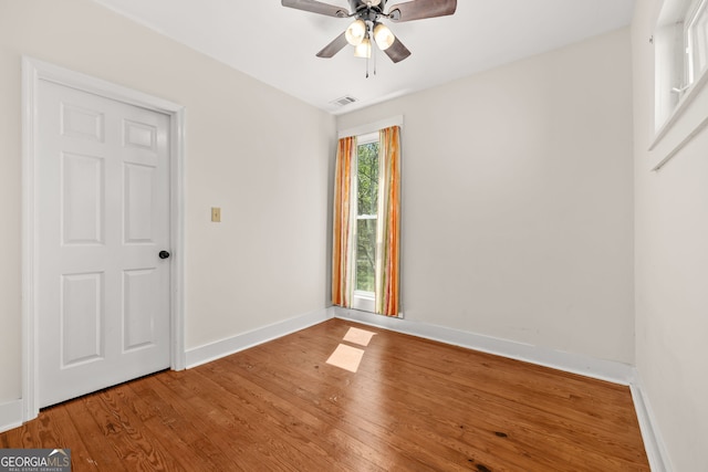 spare room featuring wood finished floors, baseboards, a ceiling fan, and visible vents