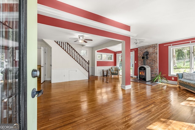 unfurnished living room with a ceiling fan, wood finished floors, and stairs