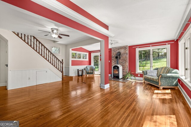 living room featuring wainscoting, wood-type flooring, a ceiling fan, and stairs