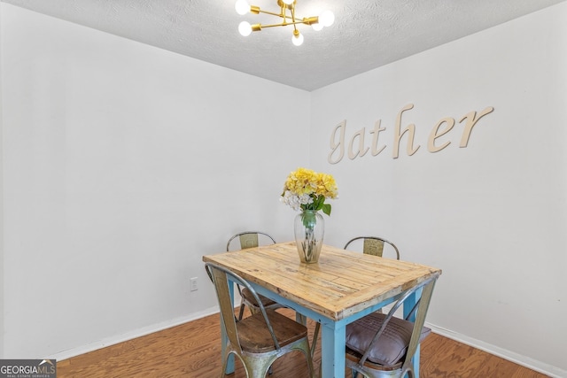 dining space with baseboards, a chandelier, and wood finished floors