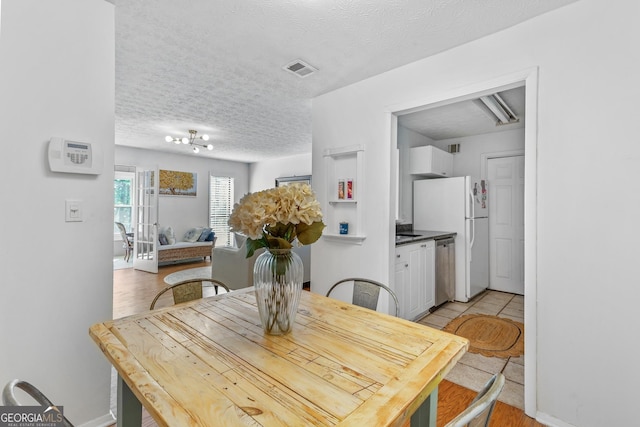 dining space featuring a textured ceiling, baseboards, and visible vents