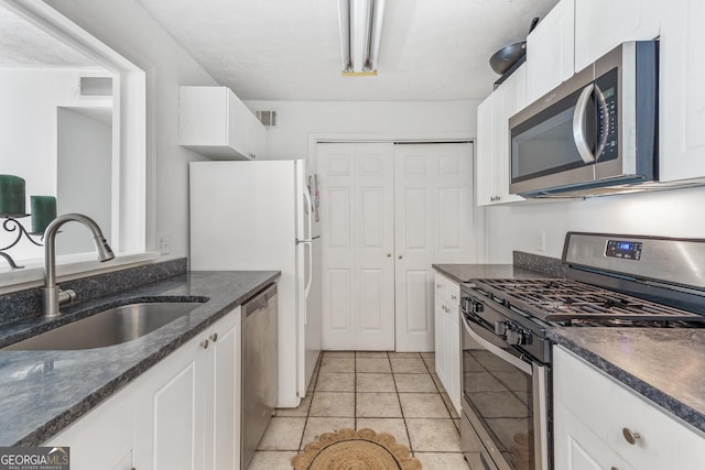 kitchen featuring light tile patterned floors, white cabinets, visible vents, appliances with stainless steel finishes, and a sink